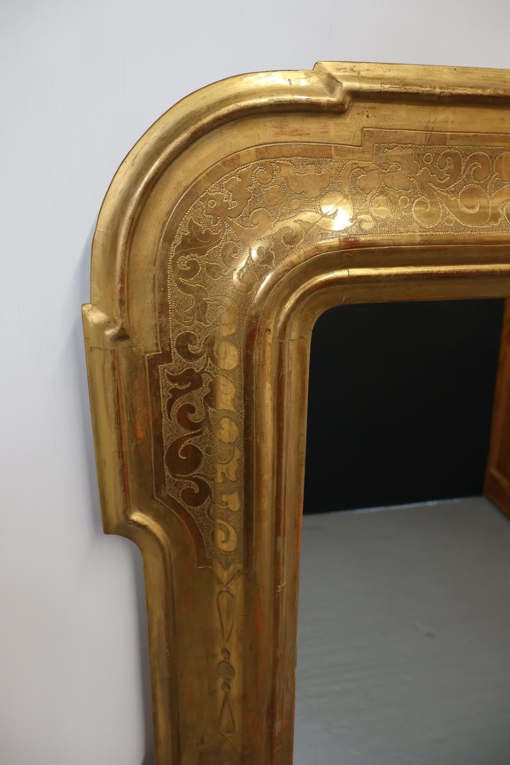 A rectangular 19th-century wall mirror featuring an ornate gold leaf giltwood frame with notched corners and incised scrollwork patterns. View IV
