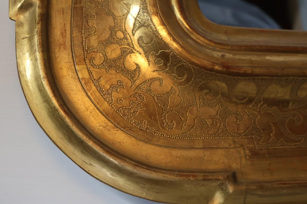 A rectangular 19th-century wall mirror featuring an ornate gold leaf giltwood frame with notched corners and incised scrollwork patterns. View V