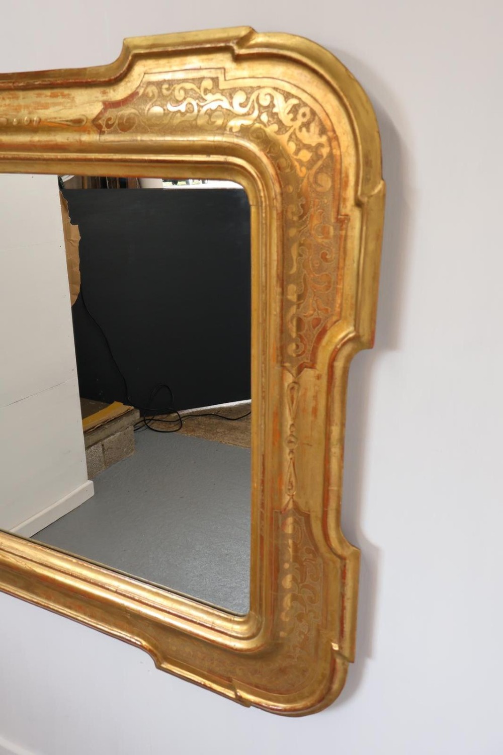 A rectangular 19th-century wall mirror featuring an ornate gold leaf giltwood frame with notched corners and incised scrollwork patterns. View VI