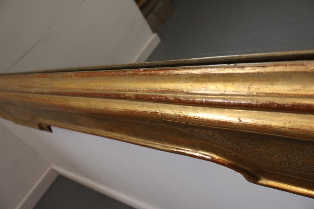 A rectangular 19th-century wall mirror featuring an ornate gold leaf giltwood frame with notched corners and incised scrollwork patterns. View VIII