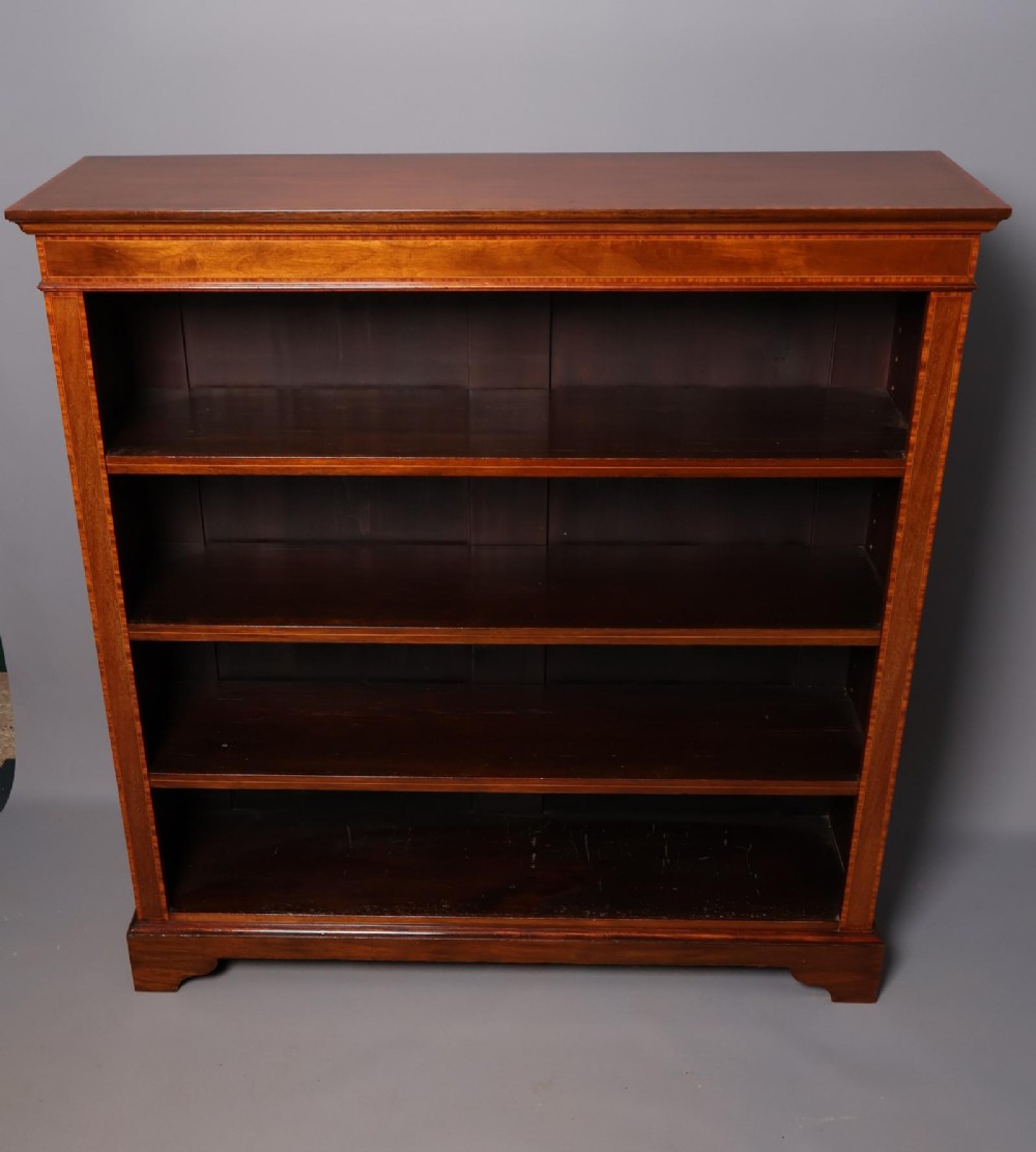 An Edwardian open-front mahogany bookcase featuring four wide shelves and decorative inlaid borders along the frame.