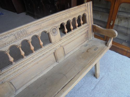fig 1. A natural light timber French country bench featuring a carved backrest with small turned spindles and panelled sections.