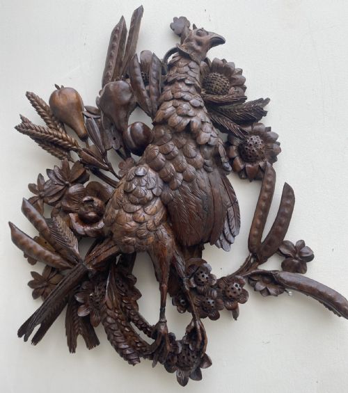 fig 1. A detailed high-relief dark timber wall plaque depicting a carved pheasant surrounded by wheat, sunflowers, and pod-like fruits.