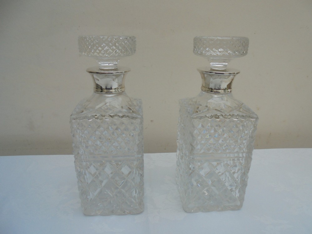 Pair of cut glass, silver top square decanters.