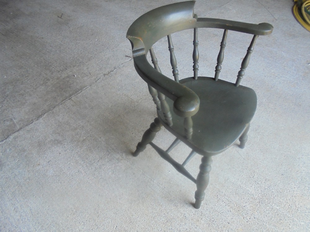 A low-backed wooden captains chair painted in dark green, featuring turned spindles, a curved armrest, and a shaped seat. View II
