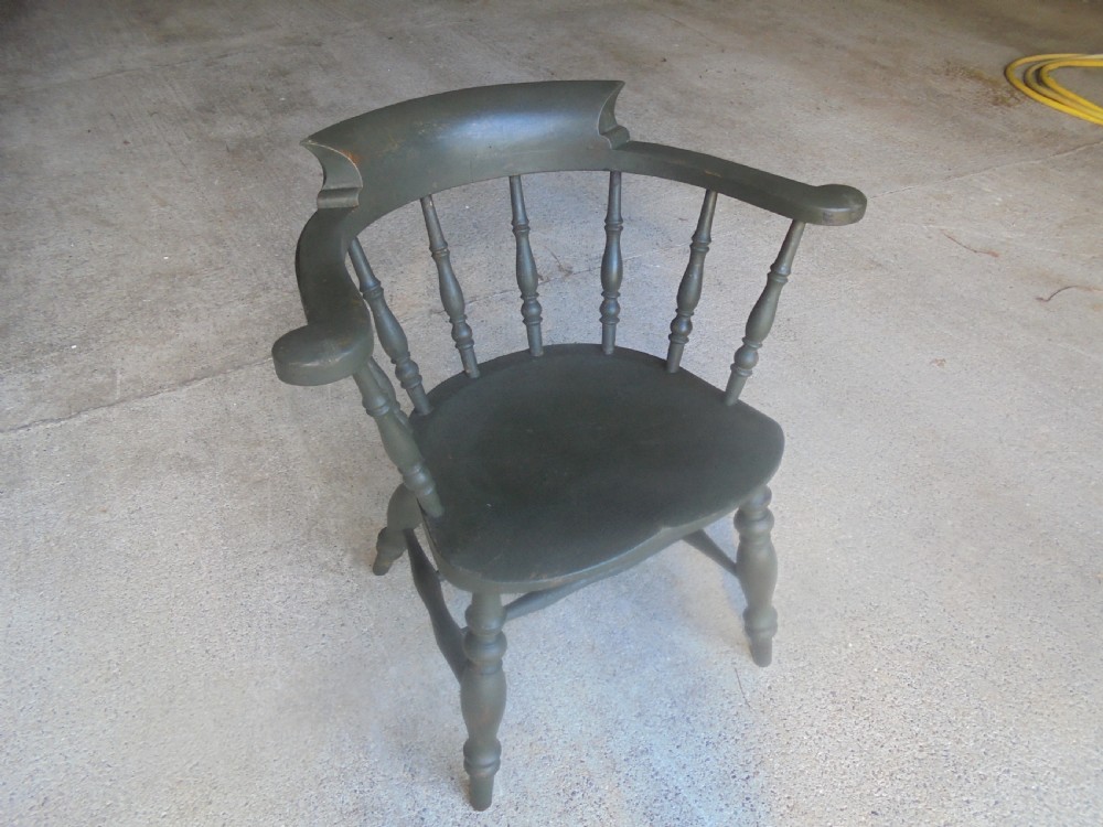 A low-backed wooden captains chair painted in dark green, featuring turned spindles, a curved armrest, and a shaped seat. View III