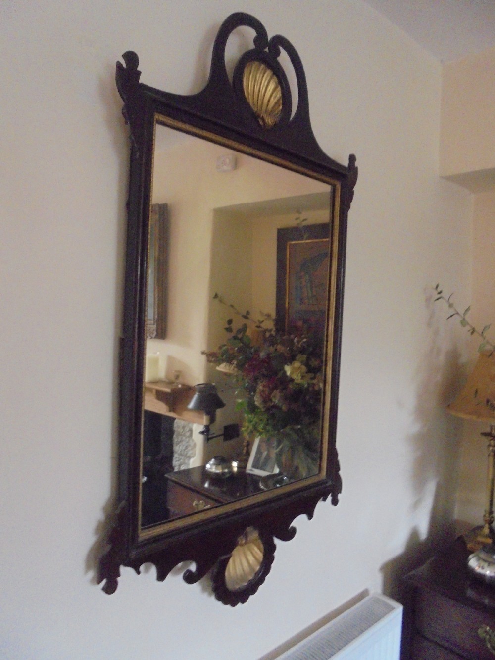 A Chippendale style dark mahogany wall mirror featuring carved fretwork cutout edges, a scrolled crest with a gilt shell motif, and a gilt slip framing the mirror glass.