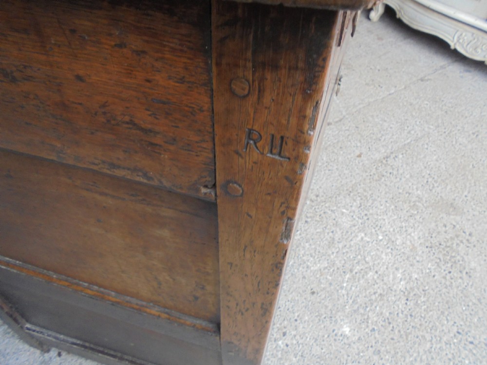 An early dark oak two-tier press cupboard featuring double geometric panelled doors, two drawers with brass teardrop handles, and turned drop finials. View IV
