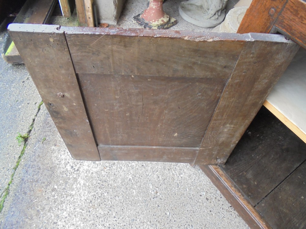 An early dark oak two-tier press cupboard featuring double geometric panelled doors, two drawers with brass teardrop handles, and turned drop finials. View V