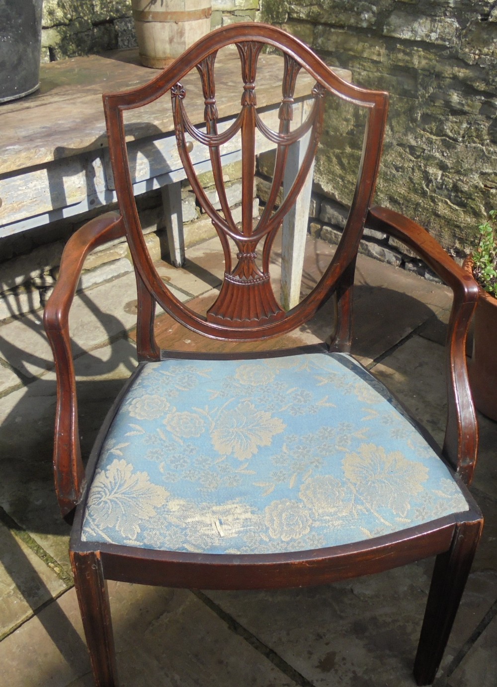 An 18th-century George III open armchair crafted from dark mahogany with a carved shield back and light blue damask seat.