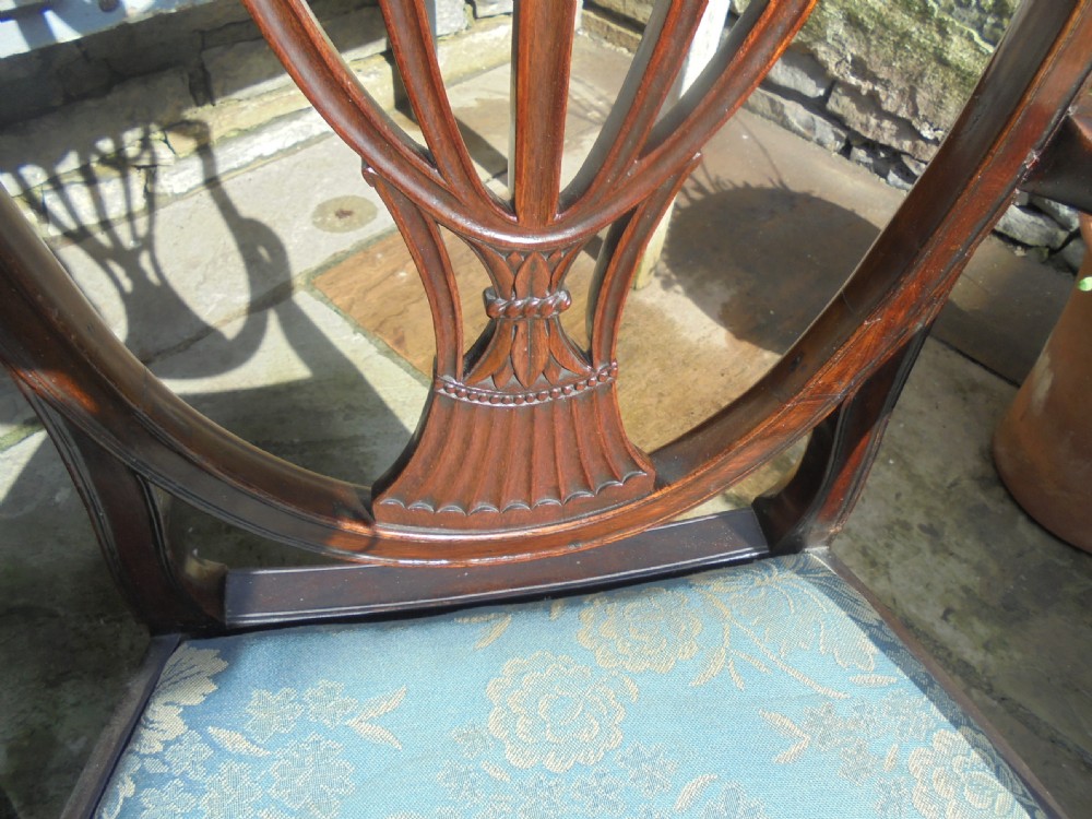 An 18th-century George III open armchair crafted from dark mahogany with a carved shield back and light blue damask seat. View VIII