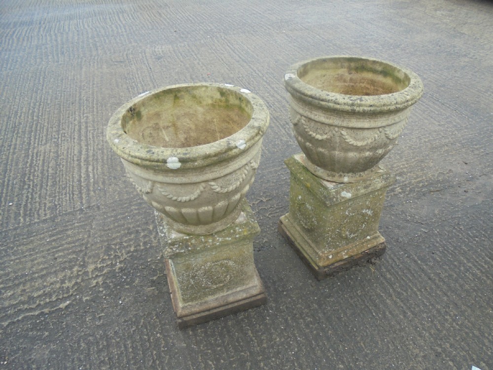 Pair of weathered  sandstone garden urns on stands 