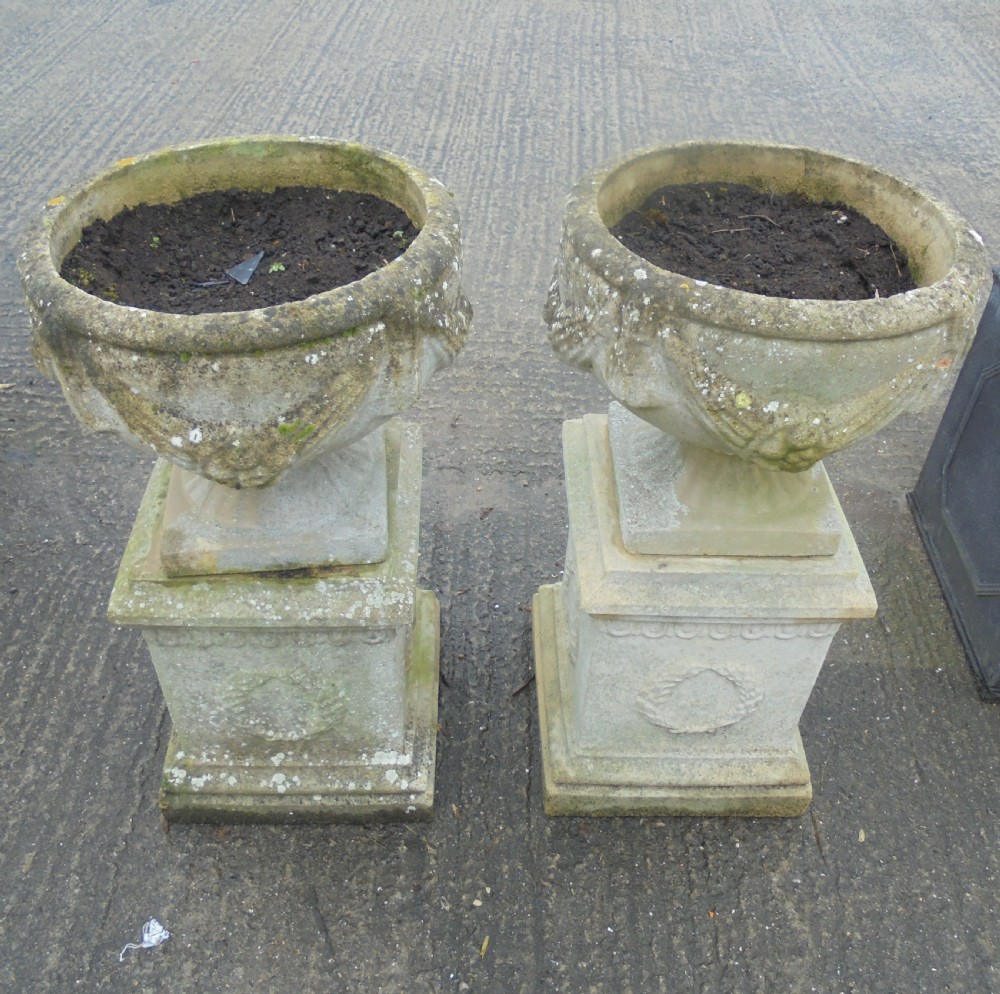 Pair of weathered sandstone garden urns on stands
