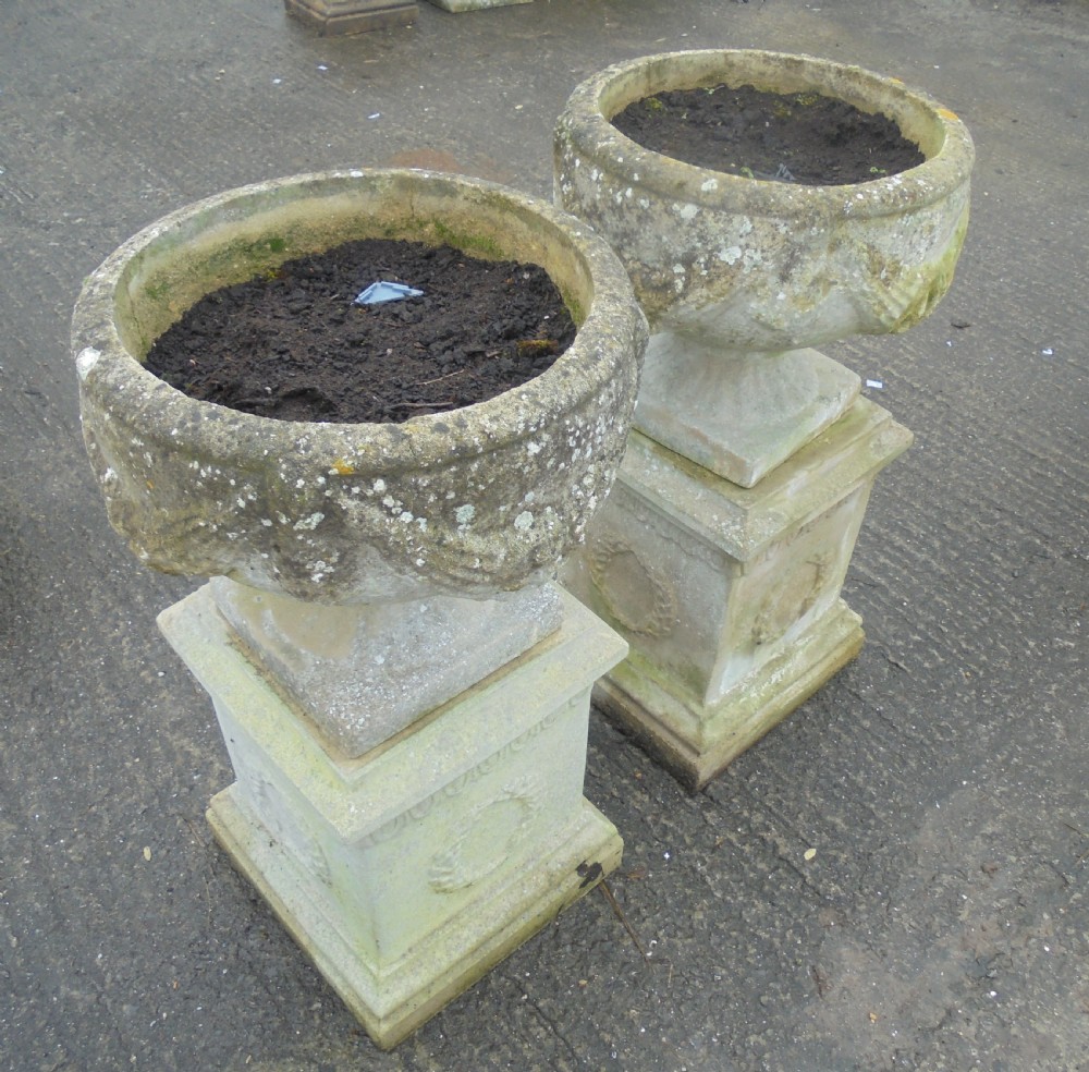 Pair of weathered sandstone garden urns on stands View II