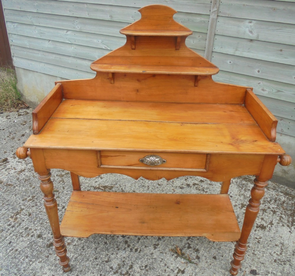 A 19th-century French cherry wood dressing table with two tiered upper shelves, turned legs, a single drawer, and an open lower shelf.