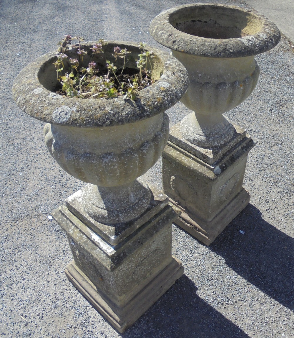 Pair of weathered sandstone garden urns on stands View II