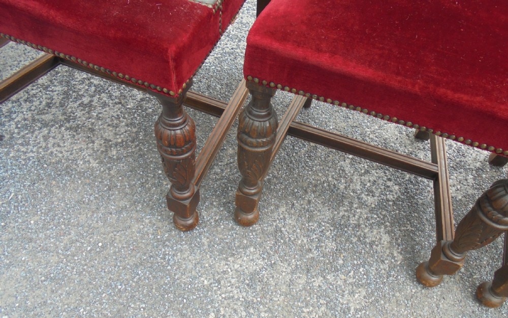 A set of seven late Victorian oak dining chairs upholstered in deep crimson velvet with brass studding, comprising six side chairs and one carver armchair. View V