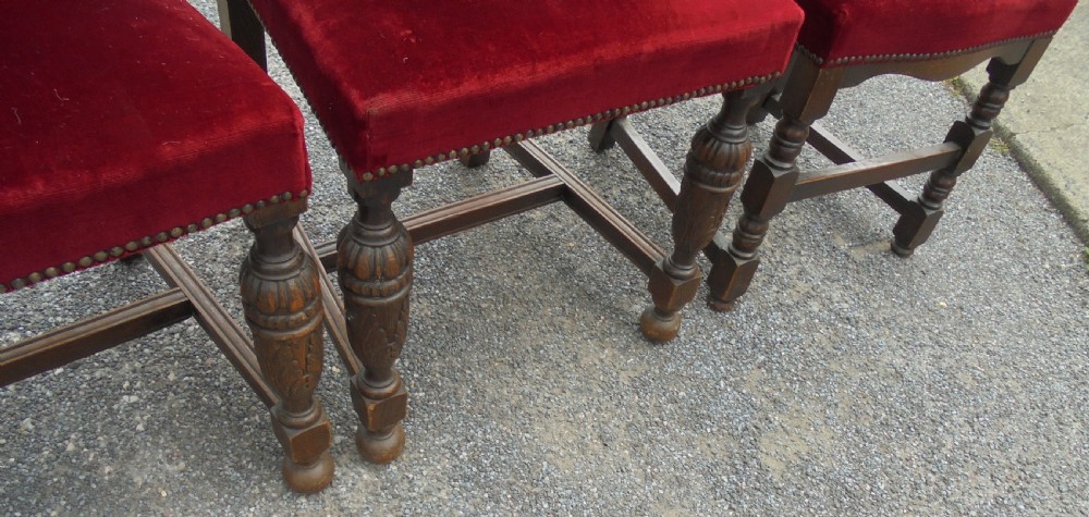 A set of seven late Victorian oak dining chairs upholstered in deep crimson velvet with brass studding, comprising six side chairs and one carver armchair. View VI