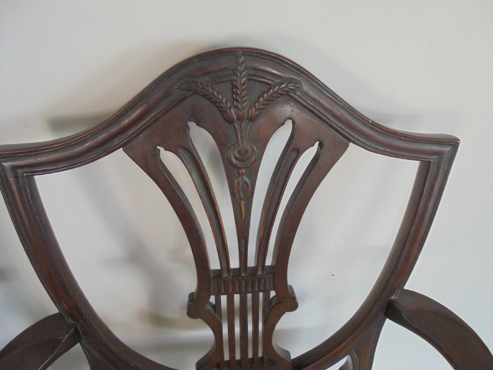 A set of eight dark mahogany dining chairs featuring carved shield backs, tapered square legs, and cream upholstered seats, including two armchairs and six side chairs. View V
