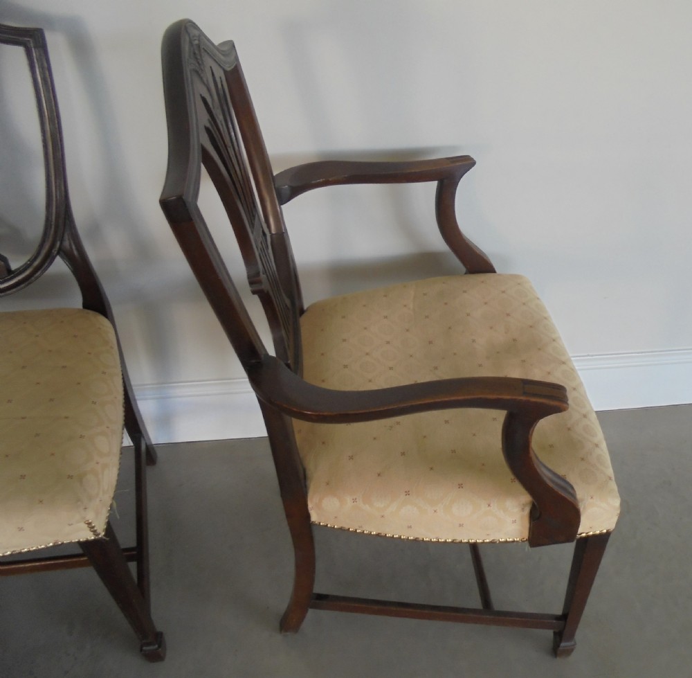 A set of eight dark mahogany dining chairs featuring carved shield backs, tapered square legs, and cream upholstered seats, including two armchairs and six side chairs. View VII