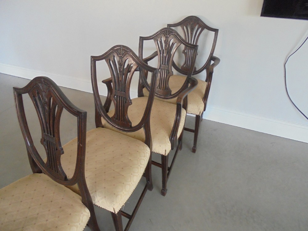 A set of eight dark mahogany dining chairs featuring carved shield backs, tapered square legs, and cream upholstered seats, including two armchairs and six side chairs. View IX