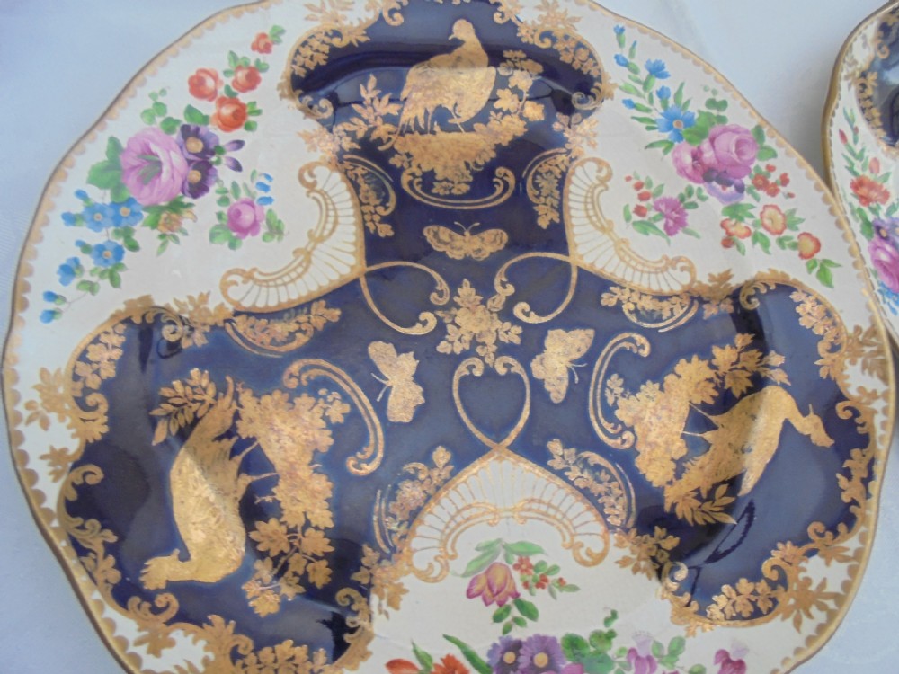 A fourteen-piece 19th-century porcelain part dessert service decorated with cobalt blue reserves, heavy gilt scrollwork, scalloped edges, and floral panels. View II