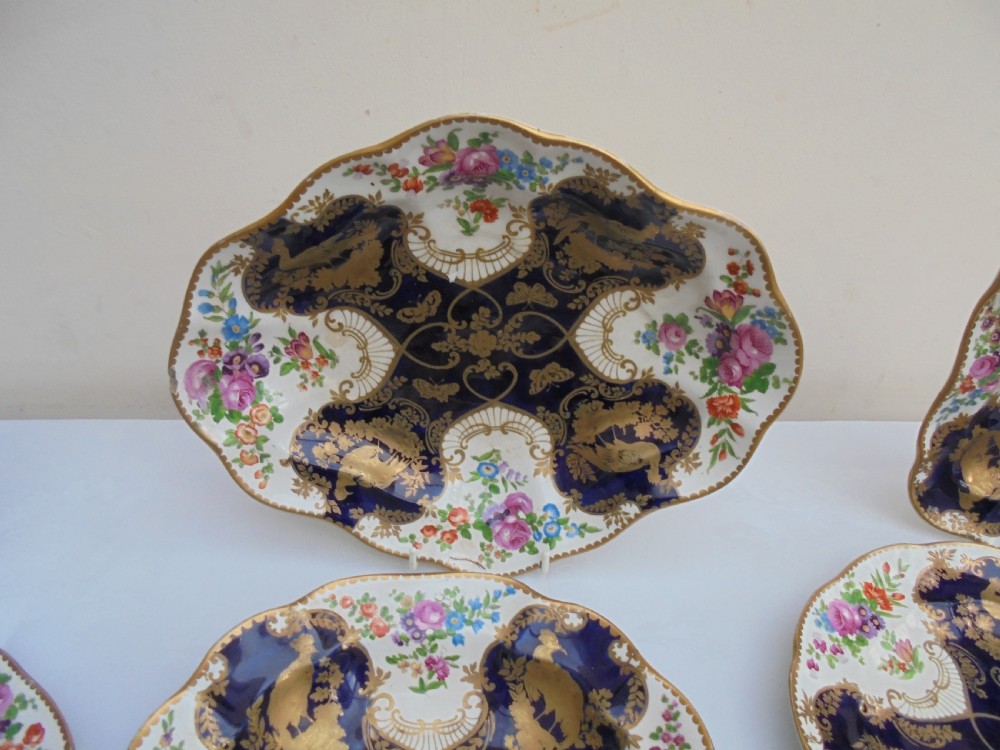 A fourteen-piece 19th-century porcelain part dessert service decorated with cobalt blue reserves, heavy gilt scrollwork, scalloped edges, and floral panels. View III