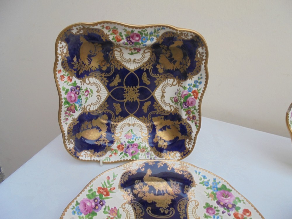 A fourteen-piece 19th-century porcelain part dessert service decorated with cobalt blue reserves, heavy gilt scrollwork, scalloped edges, and floral panels. View IV