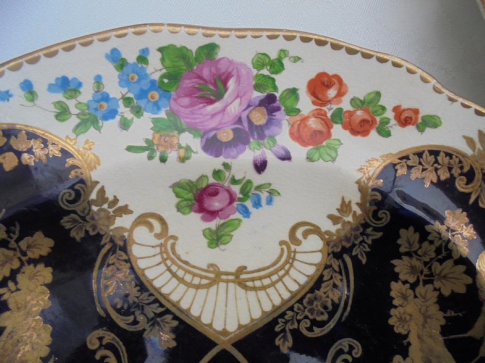 A fourteen-piece 19th-century porcelain part dessert service decorated with cobalt blue reserves, heavy gilt scrollwork, scalloped edges, and floral panels. View VI