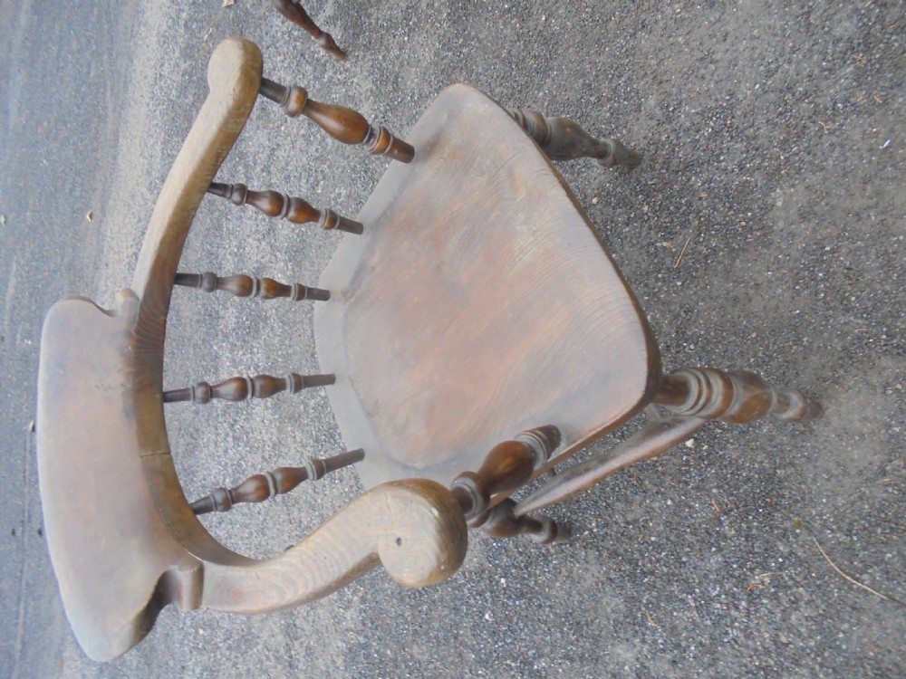 An antique ash and elm smokers bow armchair featuring a curved horseshoe armrest, turned spindles, a contoured solid saddle seat, and turned legs. View II