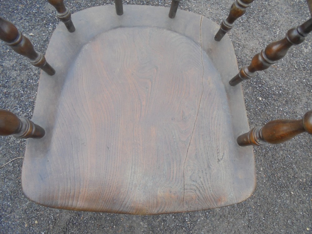 An antique ash and elm smokers bow armchair featuring a curved horseshoe armrest, turned spindles, a contoured solid saddle seat, and turned legs. View III