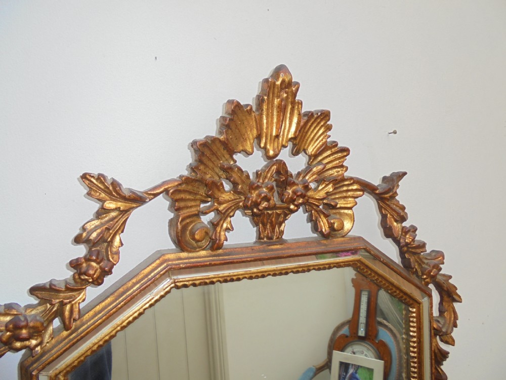 A large vertical wall mirror featuring an ornate carved giltwood frame with openwork acanthus scrolls, decorative floral cresting, and a bevelled mirror plate. View IV