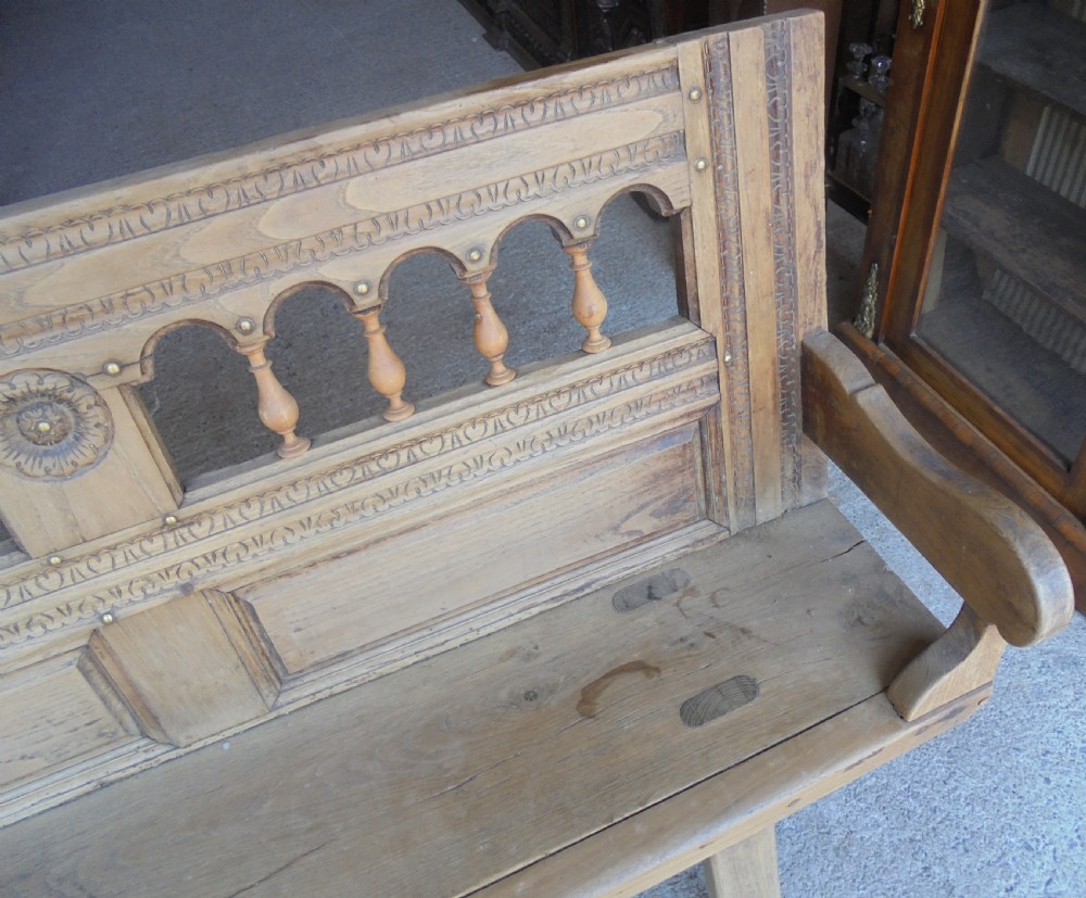 A natural light timber French country bench featuring a carved backrest with small turned spindles and panelled sections. View IV