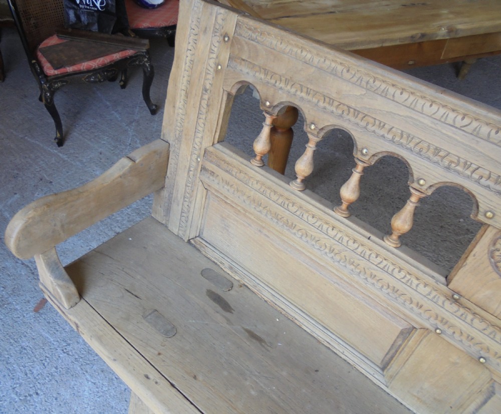 A natural light timber French country bench featuring a carved backrest with small turned spindles and panelled sections. View V