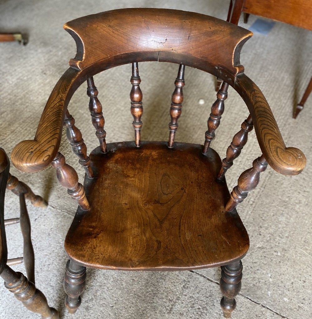A near pair of 19th-century ash and elm smokers Captain chairs with curved crest rails, turned spindles, saddle seats, and turned legs. View IV