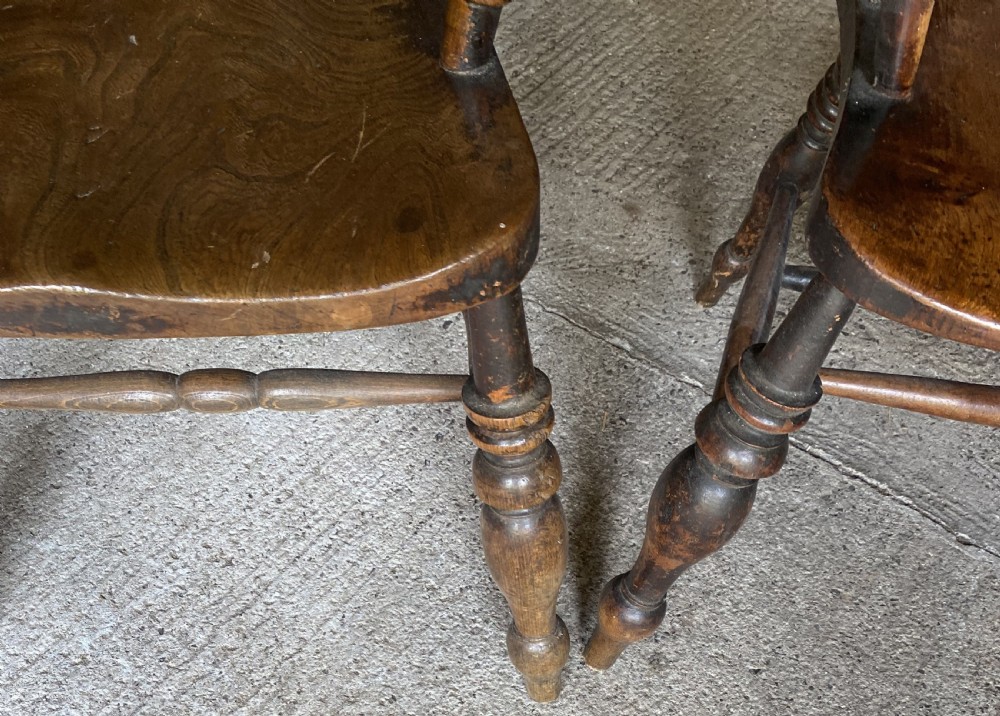A near pair of 19th-century ash and elm smokers Captain chairs with curved crest rails, turned spindles, saddle seats, and turned legs. View V