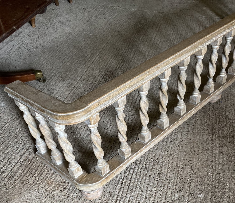 A wide limed oak fire fender featuring a row of twisted barley spindle balusters set between a top rail and bottom frame. View III