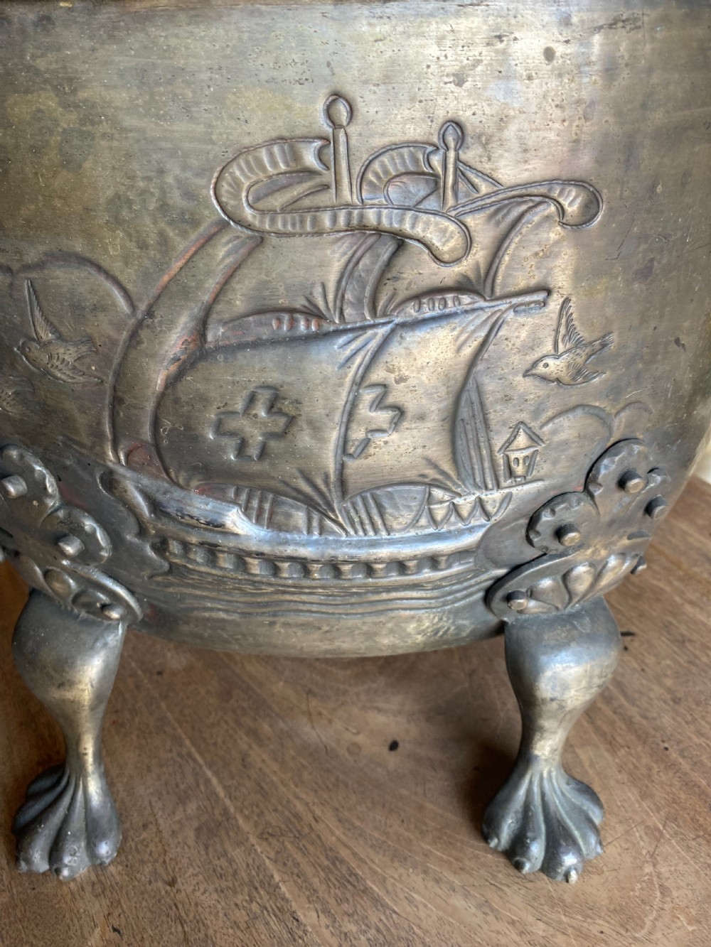 A deep bronzed brass log bucket decorated with a relief depiction of a sailing ship, supported by claw feet and featuring lion mask side handles. View IV