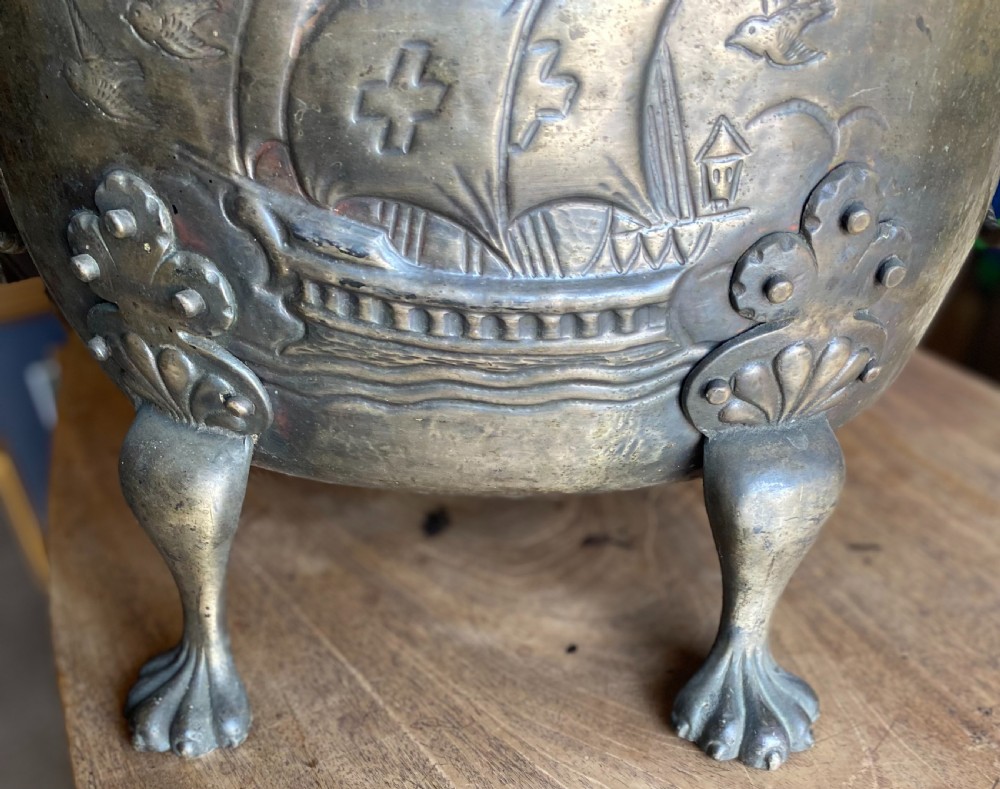 A deep bronzed brass log bucket decorated with a relief depiction of a sailing ship, supported by claw feet and featuring lion mask side handles. View V