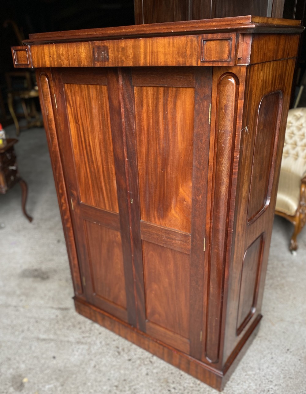 A nineteenth-century mahogany linen press cupboard featuring two panelled doors, recessed side panels, and a moulded top cornice.