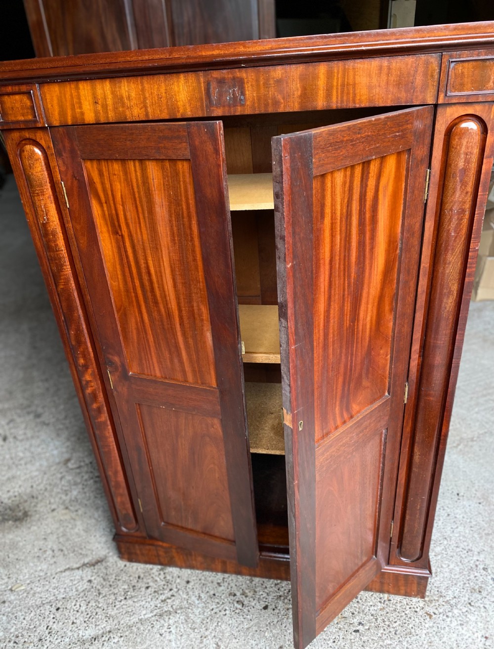 A nineteenth-century mahogany linen press cupboard featuring two panelled doors, recessed side panels, and a moulded top cornice. View VI