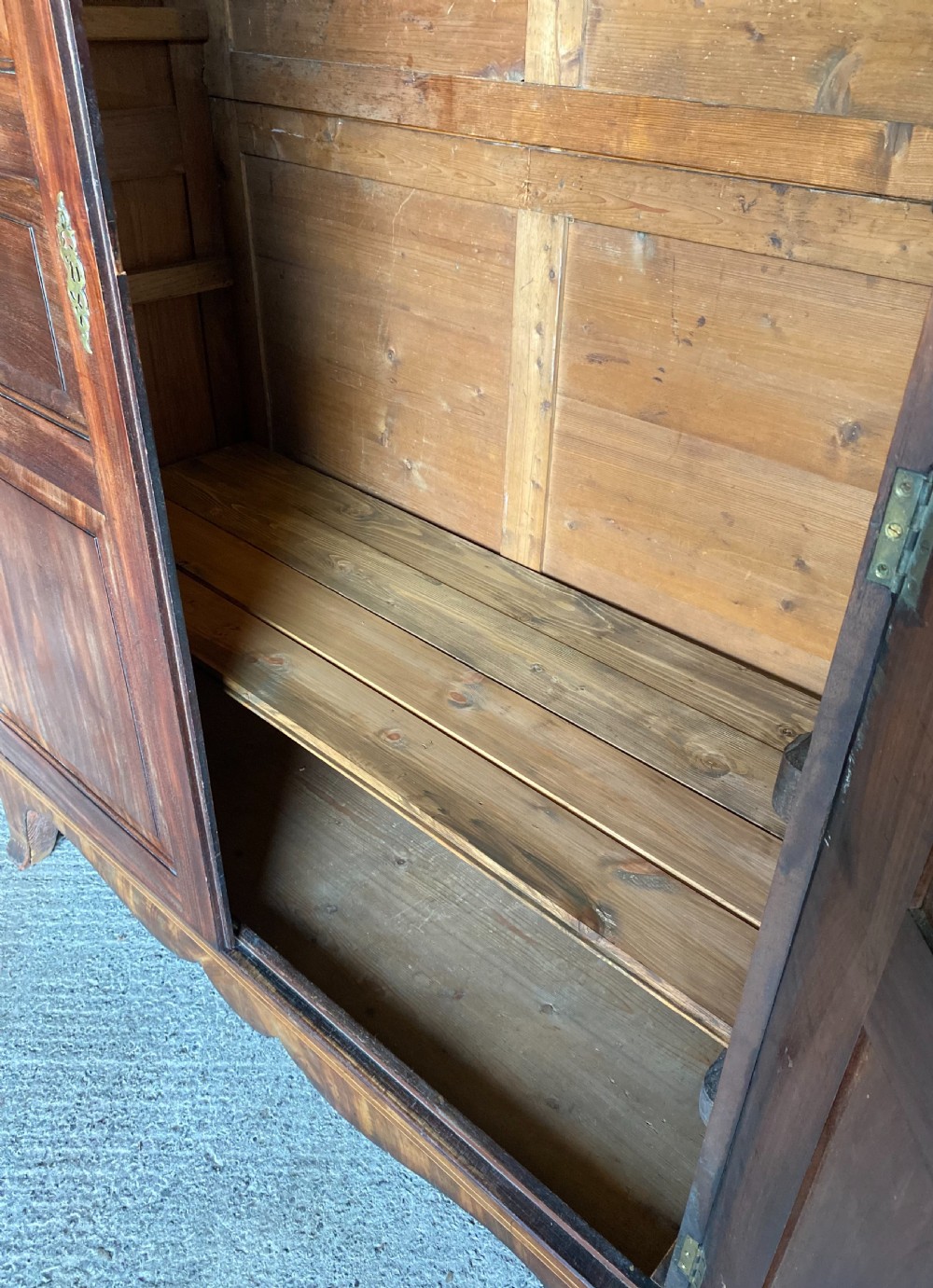An 18th-century flame mahogany Channel Island press cupboard with double fielded panel doors, brass escutcheons, and a shaped lower apron. View IV