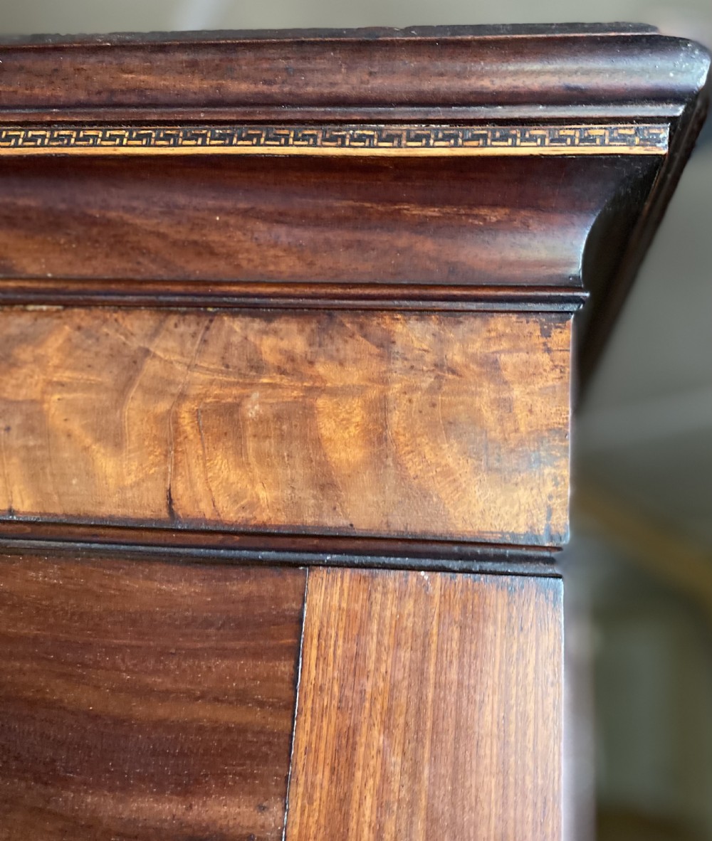 An 18th-century flame mahogany Channel Island press cupboard with double fielded panel doors, brass escutcheons, and a shaped lower apron. View VI