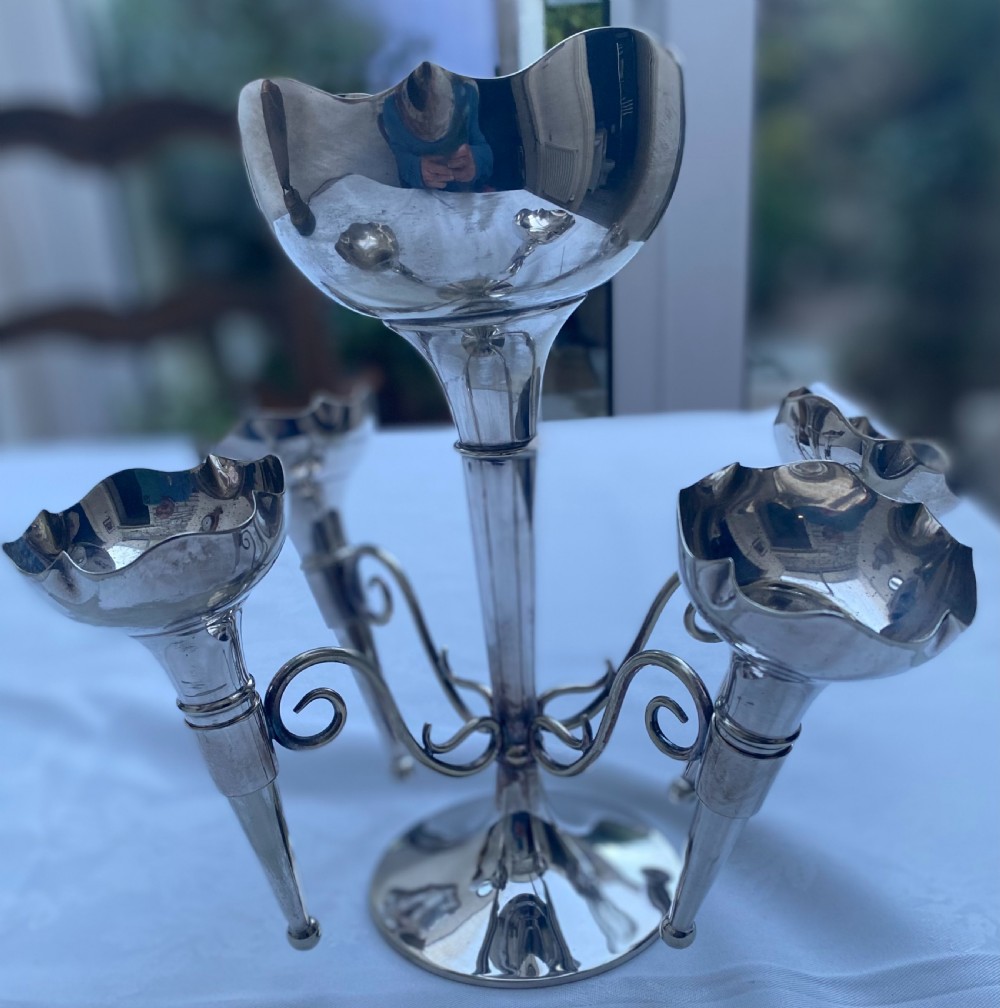 A silver-plated five-trumpet table epergne featuring a central tall trumpet vase surrounded by four smaller branching fluted vases on scroll arms. View V