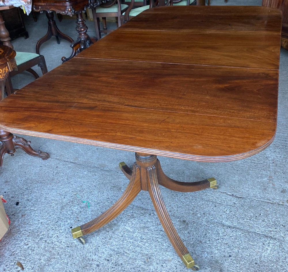 A 19th-century mahogany twin pillar dining table featuring reeded splayed legs, brass toe caps, and rounded tabletop corners. View III