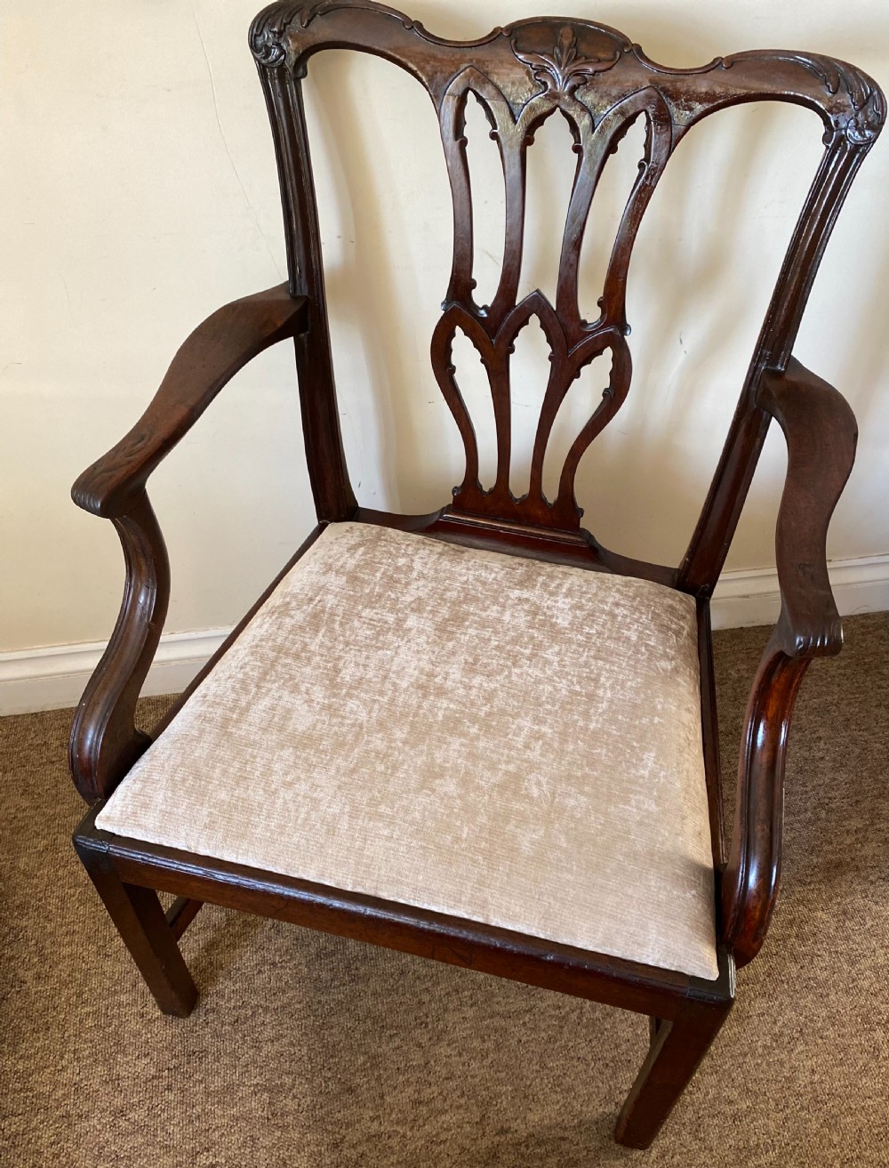 An 18th-century Chippendale mahogany armchair with a pierced carved back splat, swept arms, and a beige upholstered drop-in seat pad. View V