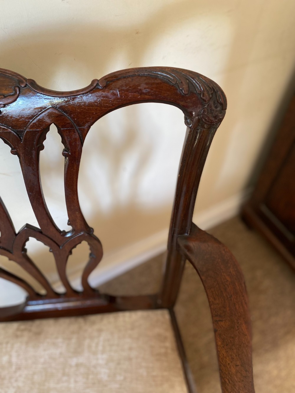 An 18th-century Chippendale mahogany armchair with a pierced carved back splat, swept arms, and a beige upholstered drop-in seat pad. View VI