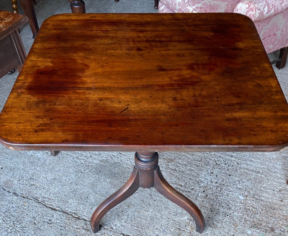 An 18th-century mahogany occasional table featuring a square top with rounded corners, supported by a central turned pedestal column and three splayed legs.