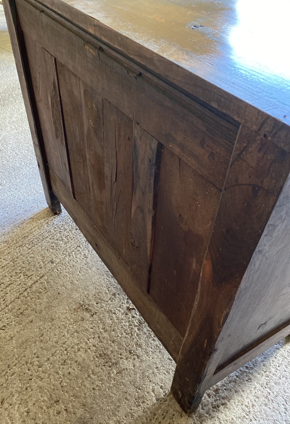 An early 18th-century French cedarwood dresser base featuring two panelled cupboard doors, long exterior brass hinges, upper drawers, and a warm brown patinated timber finish. View VII