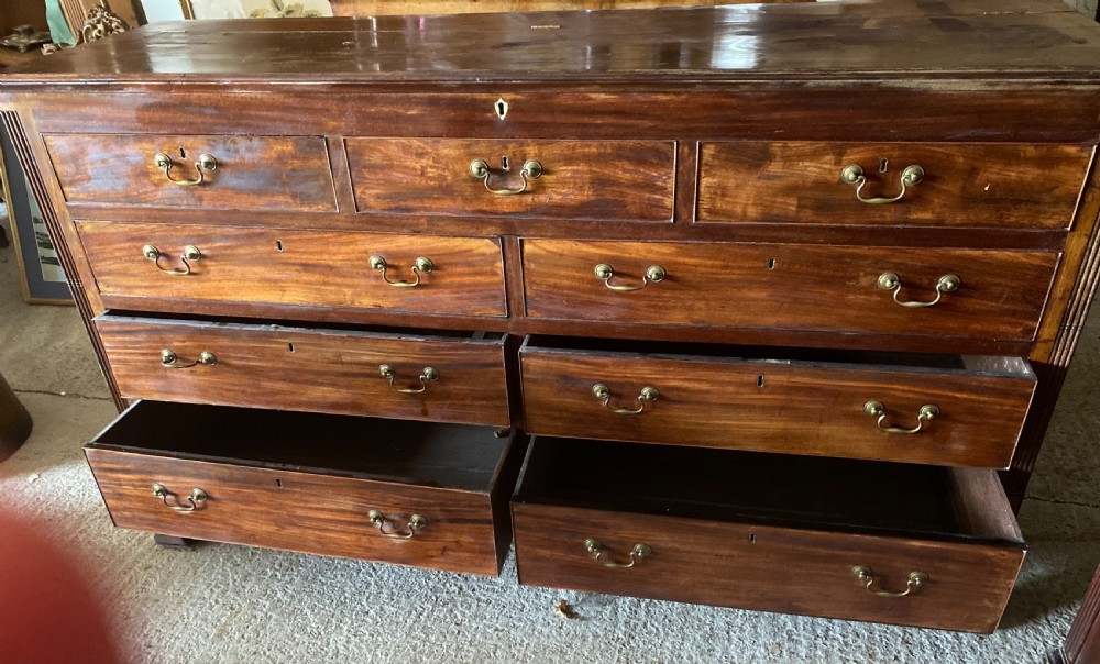 An eighteenth-century mahogany storage chest featuring a hinged top lid, multiple faux drawer fronts, brass swan-neck handles, key escutcheons, and fluted corner pilasters. View III